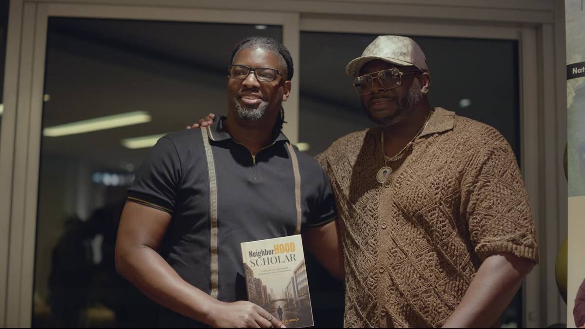Two guests holding copies of NeighborHOOD Scholar in Charlotte